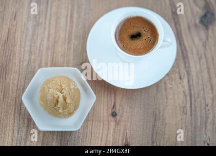 Traditionelles türkisches Dessert aus Grieß und einer Tasse Kaffee auf dem Holztisch. Lokales türkisches Dessert oder süßes Essen auf Holzhintergrund mit SE Stockfoto