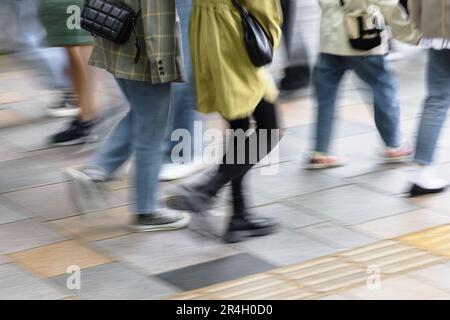 Abstraktes verschwommenes Bild einer Menschenmenge, die auf einem Bürgersteig in der Stadt läuft Stockfoto