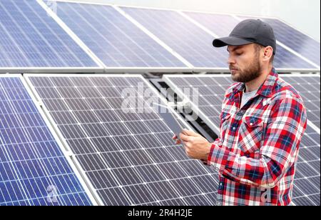 Funktion: Technischer Außendienstleiter, der ein digitales Tablet zur Leistungsbewertung von Solarpaneelen auf einer Solarenergiefarm verwendet. Stockfoto