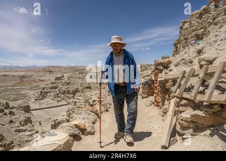 (230528) -- ZANDA, 28. Mai 2023 (Xinhua) -- Rigzin Wangzhab Walks between grottoes in Zanda County der Präfektur Ngari, Southwest China's Tibet Autonomous Region, 26. Mai 2023. Versteckt zwischen Sandsteinhügeln im abgelegenen Westen Tibets liegt ein Abschnitt von honigwabenförmigen Höhlen weit außerhalb der Reichweite der meisten Reisenden. Die 1.000 Jahre alten Höhlen in der Präfektur Ngari in der Autonomen Region Tibet, die als Donggar- und Piyang-Grotten bekannt sind, beherbergen eine der weltweit größten Sammlungen tibetischer buddhistischer Wandbilder. Rigzin Wangzhab, 75, bewacht das Gelände seit über 20 Jahren. Als ich sehr war Stockfoto