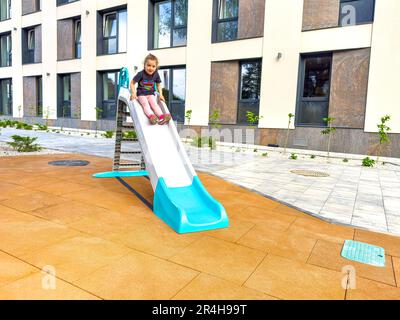 Das Kind steigt von der Kinderrutsche ab. Stockfoto