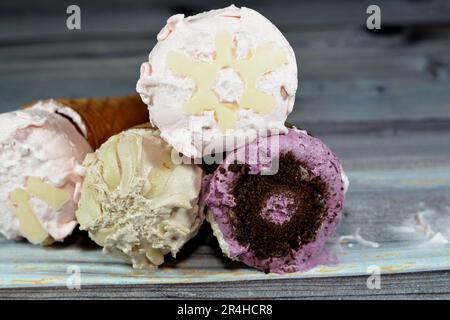 Eiscreme mit besonderen Geschmacksrichtungen in knusprigen Waffeln, schmelzendes kaltes Eis, das in einem auf Holzhintergrund, Sommer und Urlaub isolierten Wafer Keks umwirbelt wird Stockfoto