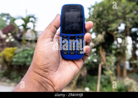 Ein Tastentelefon auf der Hand, isoliert auf natürlichem Hintergrund Stockfoto