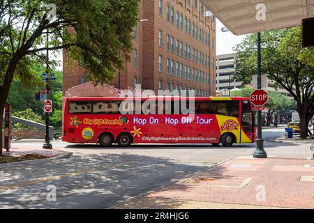 San Antonio, Texas, USA – 8. Mai 2023: Ein roter Sightseeing-Bus fährt eine enge Kurve auf einer schmalen Innenstadtstraße in San Antonio, Texas. Stockfoto