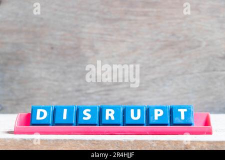 Buchstabenstein mit Wort Disrupt in rotem Regal auf Holzhintergrund Stockfoto