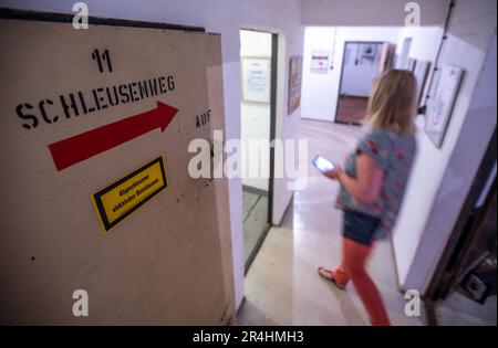 28. Mai 2023, Mecklenburg-Vorpommern, Zürow: Besucher besichtigen einen ehemaligen DDR-Bunker und sehen die Ausstellung mit einer Sammlung von DDR-Einkaufstaschen. Collector Luchs, 83, stellt insgesamt 120 Plastiktüten in der unterirdischen Betonstruktur in einem Wald bei Wismar aus. Seit Jahrzehnten sammelt der ausgebildete Schreibmaschinenleser die Taschen mit Motiven von FDJ-Treffen, der DDR Volkspolizei oder Werbegrafiken für ostdeutsche Unternehmen und wird einen Teil seiner Sammlung interessierten Besuchern im 140 Quadratmeter großen Bunker am Pfingstsonntag präsentieren. Das Bunkergebäude von t Stockfoto