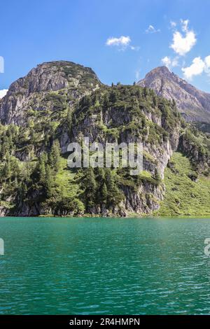 Tappenkarsee mit Wald in den Rocky Mountains in Osterreich. Vertikaler Panoramablick auf den grünen Alpensee und die Steinberge in Europa am Sommerreisetag. Stockfoto