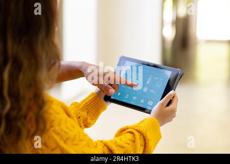 Birassistische junge Frau, die Smart Home mit einem digitalen Tablet steuert, und ein Mann, der auf eine Anwendung zeigt Stockfoto