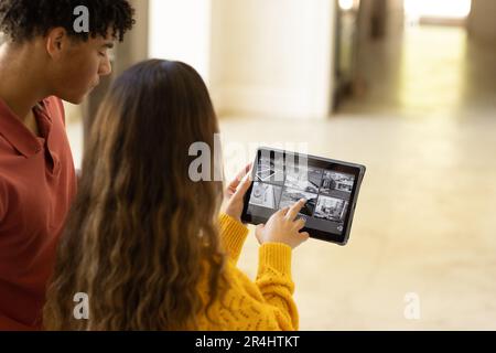Birassisches junges Paar, das Smart Home mit Videokamera über ein digitales Tablet steuert Stockfoto