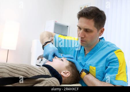 Osteopath behandelt das Atmungssystem des Schuljungen auf der Couch in der Klinik Stockfoto