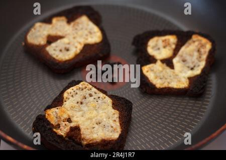 Drei Käsesandwiches, die in der Pfanne zu schwarz verbrannt wurden. Stockfoto