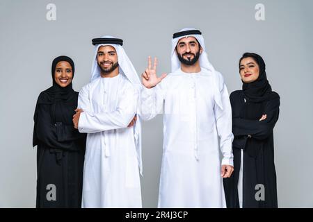 Wunderschöne arabische Frauen aus dem Nahen Osten mit traditionellem Abaya-Kleid und ein Mann aus der Mitte ostern, der Kandora im Studio trägt - Gruppe arabisch-muslimischer Erwachsener Portier Stockfoto