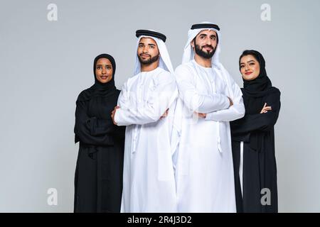 Wunderschöne arabische Frauen aus dem Nahen Osten mit traditionellem Abaya-Kleid und ein Mann aus der Mitte ostern, der Kandora im Studio trägt - Gruppe arabisch-muslimischer Erwachsener Portier Stockfoto