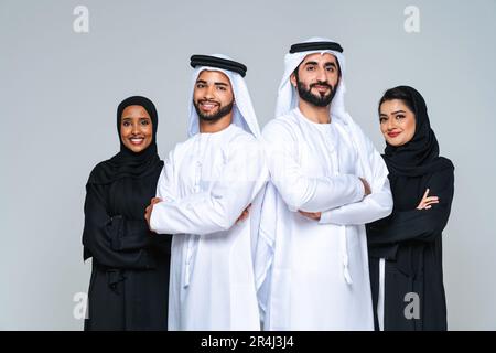 Wunderschöne arabische Frauen aus dem Nahen Osten mit traditionellem Abaya-Kleid und ein Mann aus der Mitte ostern, der Kandora im Studio trägt - Gruppe arabisch-muslimischer Erwachsener Portier Stockfoto