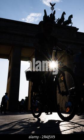 Berlin, Deutschland. 28. Mai 2023. Radfahrer fahren im Hintergrund der untergehenden Sonne über den Pariser Platz vor dem Brandenburger Tor. Kredit: Monika Skolimowska/dpa/Alamy Live News Stockfoto