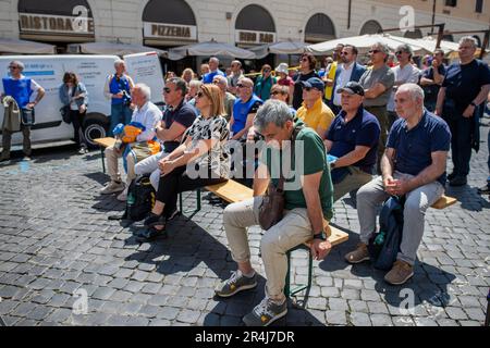 Unter der Sonne sitzende, nachdenkliche Demonstranten hören den Reden während der Demonstration zu. Demonstration auf der Piazza Santi Apostoli, organisiert von der „Associazione Pensionati Polizia di Stato 94°Corso Antiochia“ (Staatspolizeiverband 94., Kurs Antiochia), um die Normalisierung der Transformationskoeffizienten zu fordern, die im Haushaltsgesetz 2021 vorgesehen sind und von der INPS (der nationalen Sozialversicherungsanstalt) auf die Renten angewandt werden. Und sie den Angehörigen der Arma dei Carabinieri oder der Feuerwehr gleichstellen. Stockfoto