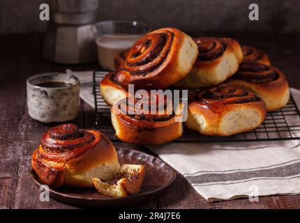 Hefeteig mit Zimt mit Mohnsamen, Rosinen und kandierten Früchten, serviert mit Kaffee. Rustikaler Stil. Stockfoto