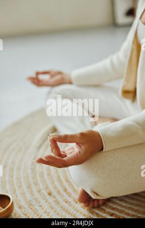 Nicht wiedererkennbare afroamerikanische Frau, die in Lotus-Pose auf dem Boden sitzt. Stockfoto