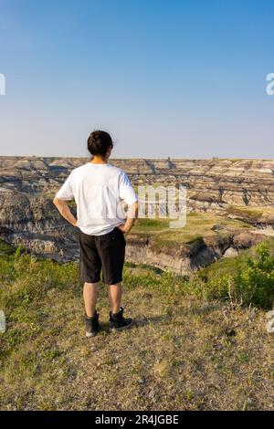 Mann steht am Rand der Klippe mit Blick auf den Canyon von Drumheller Alberta Stockfoto