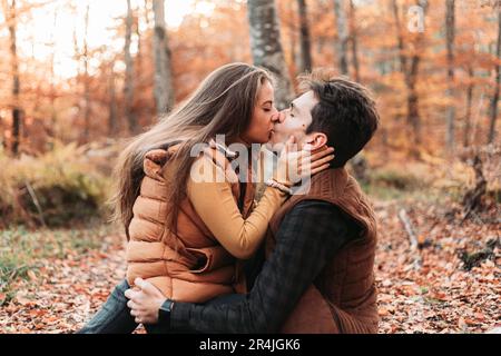Ein junges Paar, das viel Spaß im Wald hat, sich küsst Stockfoto