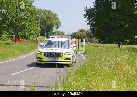 RideLondon Classique 2023 Stage 2 führt durch das Dorf Layer-de-la-Haye in der Nähe von Colchester in Essex. Ein Polizeiauto mit Polizisten, die winken Stockfoto