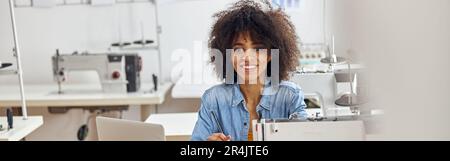 Eine lächelnde afroamerikanische Modedesignerin zeichnet Kleider mod Stockfoto