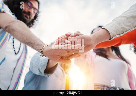 Kleiner Blickwinkel einer Gruppe junger Menschen, die ihre Hände zusammenstapeln und für ein Arbeitsprojekt zusammenarbeiten. Das Team der besten Kollegen legt die Hände übereinander und steht draußen. Einheit und Partnerschaft. Hochwertiges Foto Stockfoto