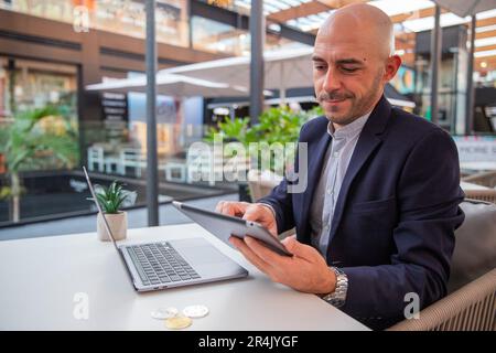 Ein Kryptowährungshändler überwacht den Markt mit seinem Tablet Stockfoto