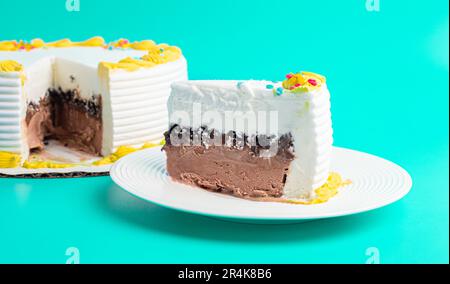 Ein Stück Vanille- und Schokoladeneiskuchen auf blauem Hintergrund Stockfoto