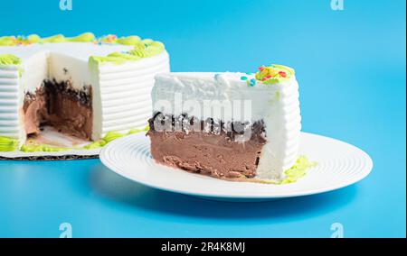 Ein Stück Vanille- und Schokoladeneiskuchen auf blauem Hintergrund Stockfoto