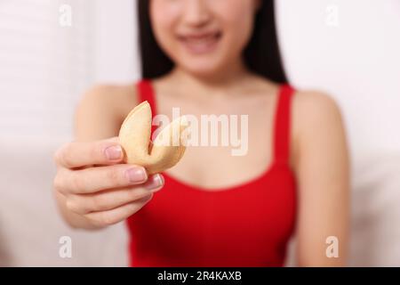 Junge Frau mit leckerem Glückskeks, mit Voraussage drinnen, Nahaufnahme Stockfoto