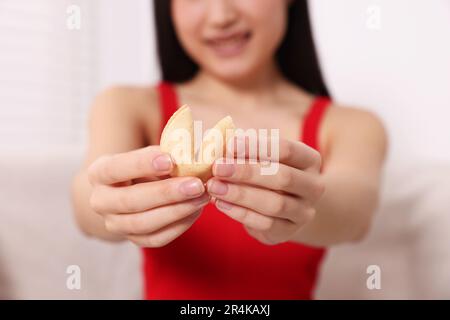 Junge Frau mit leckerem Glückskeks, mit Voraussage drinnen, Nahaufnahme Stockfoto