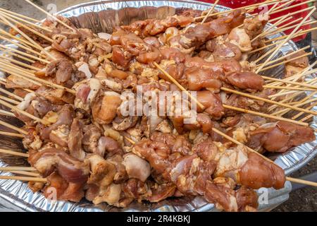 Ein großes Tablett mit philippinischem Barbecue, mariniertem Schweinefleisch, das auf Spieße geschoben wird, fertig zum Kochen Stockfoto