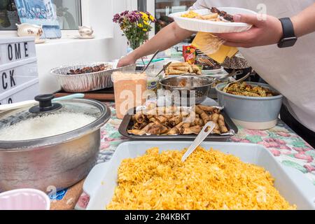 Ein Selbstbedienungsbuffet mit philippinischen Gerichten auf einer Party mit einer großen Auswahl an Gerichten U=einschließlich Reis, Frühlingsrolle und Nudelsalat Stockfoto