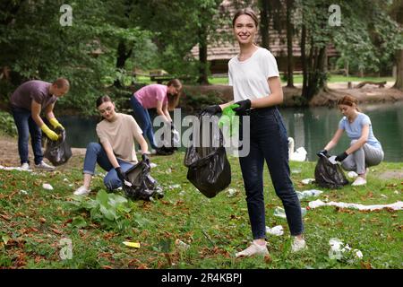 Eine Gruppe von Leuten mit Plastiktüten, die Müll im Park sammeln Stockfoto