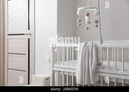 Modernes Kinderbett mit Babymobil im Kinderzimmer. Innendesign Stockfoto