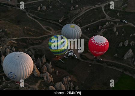 Heißluftballons aus der Vogelperspektive, die zu Beginn eines Sonnenaufgangs abheben, in der Nähe des Zelve Open Air Museum, Kappadokien, Türkei Stockfoto