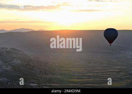 Ein Heißluftballon mit Silhouette vor dem Sonnenaufgang über Capadoccia. Stockfoto