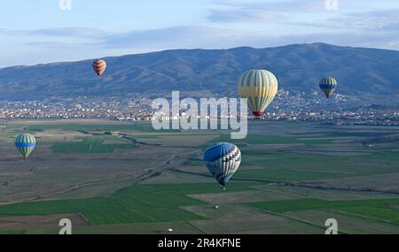 Heißluftballons fliegen über landwirtschaftliche Felder in der Nähe von Avanos, Capadoccia, Türkei Stockfoto