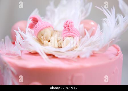 Dekoration eines Kuchens für eine Familie Taufe rosa Kuchen mit Fußabdrücken eines kleinen Kindes auf Engelsflügeln und Baby in rosa Windel ein Mädchen, wie man das Geschlecht des Kindes mithilfe eines Kuchens herausfinden kann Stockfoto