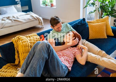 Ein junges Paar, Mann und Frau, die sich auf dem Sofa ausruhen und das Eheleben genießen Stockfoto