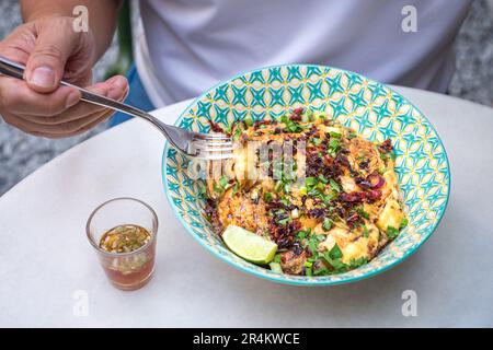 Ein Mann, der Omelett auf einer Schüssel Reis isst, thailändisches Essen. Draufsicht. Stockfoto