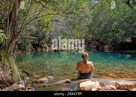 Eine Frau, die an den Blauen Lagunen auf Hinchinbrook Island sitzt Stockfoto