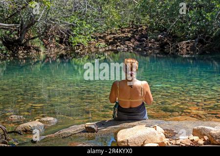 Eine Frau, die an den Blauen Lagunen auf Hinchinbrook Island sitzt Stockfoto