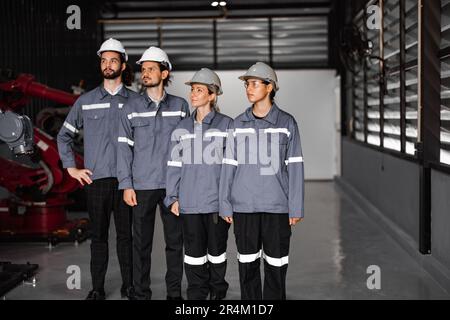 Selbstbewusstes Roboterteam, darunter Frauen in einem nicht typischerweise von Männern dominierten Feld, kreuzt die Arme und repräsentiert das Engagement des Unternehmens für Vielfalt und Inklusion Stockfoto