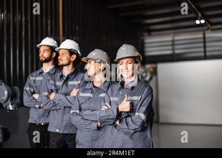 Selbstbewusstes Roboterteam, darunter Frauen in einem nicht typischerweise von Männern dominierten Feld, kreuzt die Arme und repräsentiert das Engagement des Unternehmens für Vielfalt und Inklusion Stockfoto