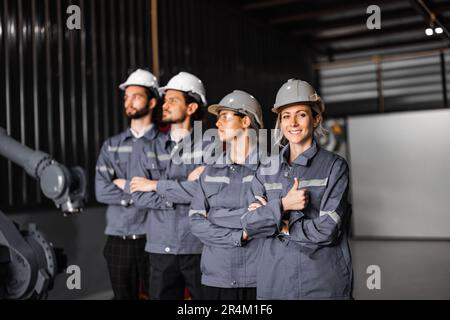 Selbstbewusstes Roboterteam, darunter Frauen in einem nicht typischerweise von Männern dominierten Feld, kreuzt die Arme und repräsentiert das Engagement des Unternehmens für Vielfalt und Inklusion Stockfoto