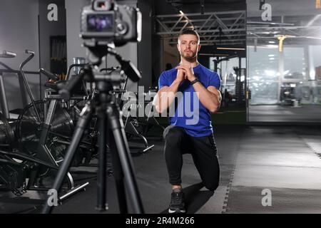 Ein Mann nimmt das Workout mit der Kamera im Fitnessstudio auf. Online-Fitnesstrainer Stockfoto