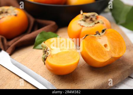 Ganze und geschnittene köstliche reife Persimonen auf dem Tisch, Nahaufnahme Stockfoto