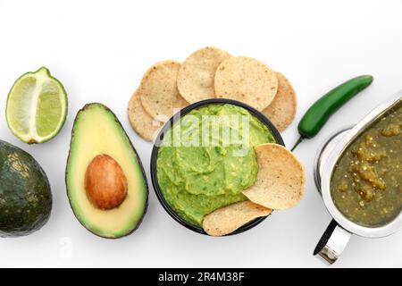 Köstliche Guacamole aus Avocados, Nachos und grünem Pfeffer auf weißem Hintergrund, Draufsicht Stockfoto